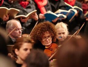 Frau spielt Geige, im Hintergrund ist der Kammerchor